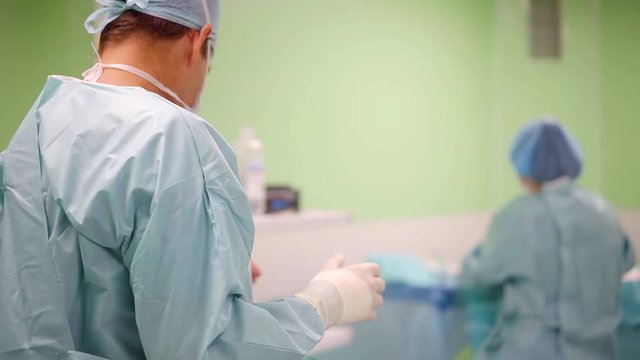 Male surgeon and female assitant preparing for upcoming operation.