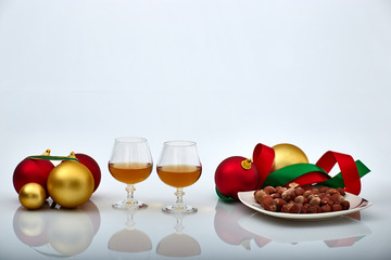 Pair of liquor glasses with Christmas ornaments and hazelnuts