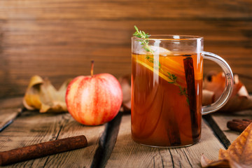 Apple tea, cinnamon sticks, wooden background, retro rustic style, autumn mood, fallen dry leaves