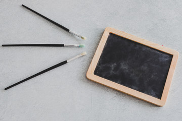 paintbrushes next to small blackboard with copyspace