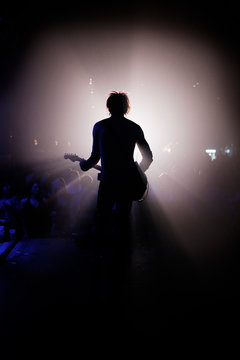 Rear view of man playing guitar at concert
