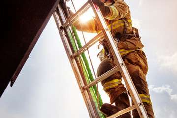 Low angle view of firefighter climbing ladder against sky © Cavan for Adobe