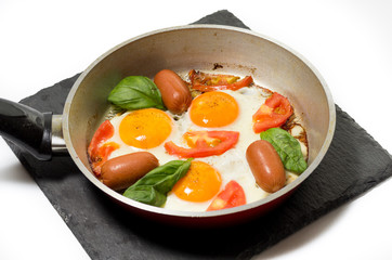Fried eggs in a pan on a slate stand.