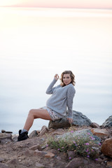 Fototapeta na wymiar Pregnant woman sitting on a rock near the water