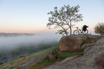 Bicycle over misty canyon, river and stones