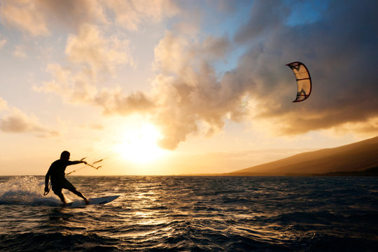 Silhouette man kiteboarding in sea against sky during sunset