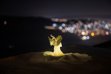christmas angel on blur bokeh city lights at night on background. Little white guardian angel in...