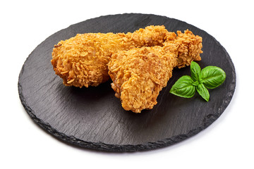 Roasted Breaded Chicken Legs (drumsticks) on a slate shale plate, isolated on white background. Close-up
