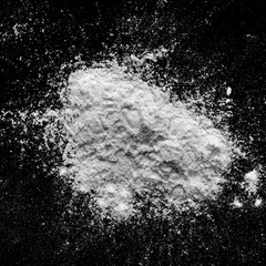 Isolated natural white flour powder texture effect on clean black background. Organic baking element close-up.