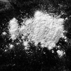 Isolated natural white flour powder texture effect on clean black background. Organic baking element close-up.