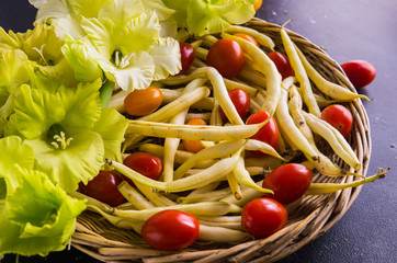 Cherry tomatoes and bean pods along with flowers on the table. Everything is grown on an organic farm.