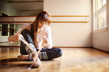 Dancer tying ballet shoes in dance studio © Cavan for Adobe