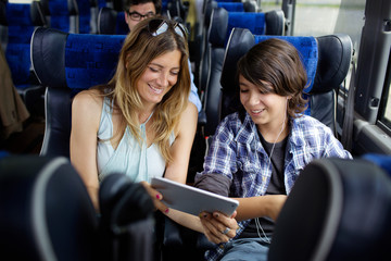 Happy mother and son looking at laptop computer while sitting in bus © Cavan for Adobe