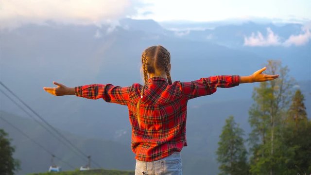 Beautiful happy little girl in mountains in the background of fog