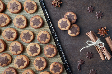 Christmas cookies with chocolate star pattern on baking paper with cinnamon and anise