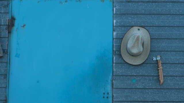 Concept of the cowboy lifestyle. Old blue wood door. Cowboy hat and knife near the door.