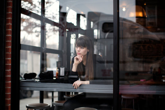 Thoughtful woman seen through glass window in cafe