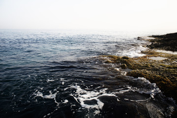 Aerial top view of sea waves hitting rocks on the beach with turquoise sea water. Amazing rock cliff seascape in the coastline. Aerial view of sea waves and fantastic Rocky coast. Mediterranean Sea.
