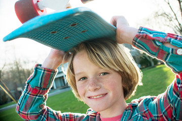 Portrait of boy carrying skateboard on head © Cavan for Adobe