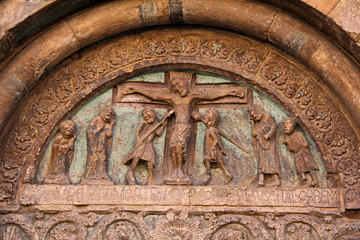 Cristo in croce tra due centurioni; rilevo di scuola Antelamica. Arco del portale della pieve di Santa Maria in Castello, detta la Sagra, a Carpi - obrazy, fototapety, plakaty