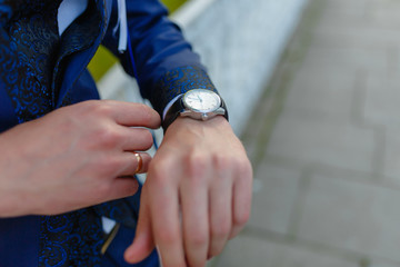 A man in a luxurious blue suit looking at a luxurious watch. Businessman checks with the clock.