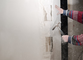 reconstruction and renovation, craftsman removes a part of the wall with a hammer for the interior fitting in a construction site of a residential house, copy space