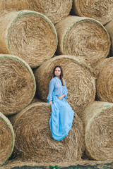 Beautiful woman in a dress on haystacks.