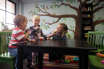 Children and nanny eating artificial toys at table in preschool © Cavan for Adobe