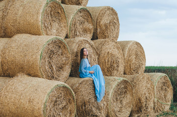 Beautiful woman in a dress on haystacks.