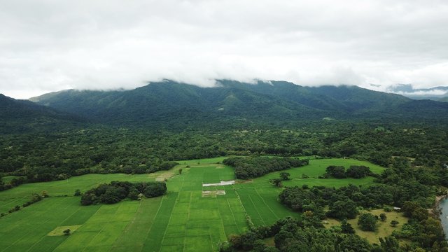 Aerial view of patchwork field and lush greenery of countryside with hills on the background in Zambales, Philippines 