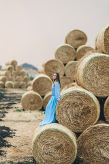 Beautiful woman in a dress on haystacks.