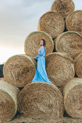 Beautiful woman in a dress on haystacks.