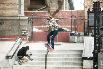 Man photographing friend skateboarding on railing at skateboard park © Cavan for Adobe