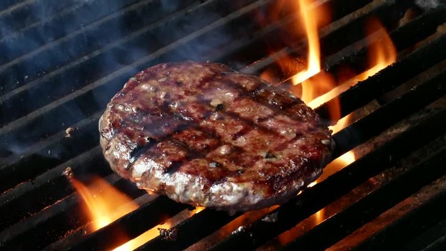 Single hamburger is cooking on the grill