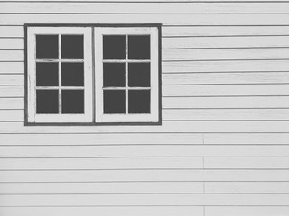The old white wooden windows on white artificial wood wall background in black and white on film tone and vintage style
