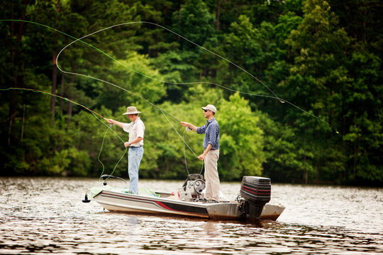 Men casting fishing rods while fly fishing in lake