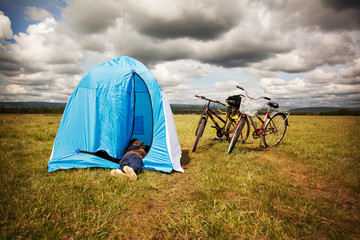 Boy relaxing in tent on field against cloudy sky © Cavan for Adobe