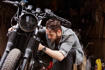 Man examining motorcycle outside workshop © Cavan for Adobe