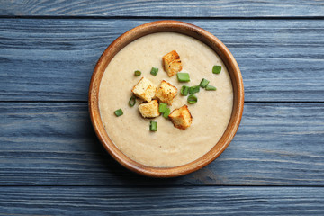 Obraz na płótnie Canvas Bowl of fresh homemade mushroom soup on wooden background, top view