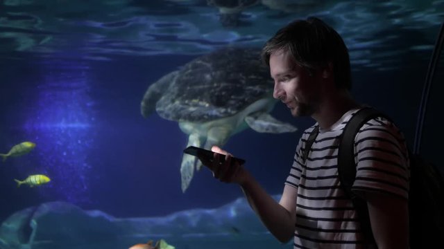 Asian tourist man taking a photo of turtle in an aquarium tank voice recognition ai speech audio message note