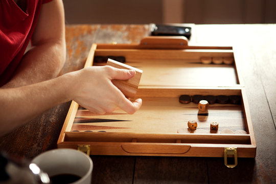 Cropped image of man throwing dice cup at table