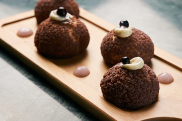Chocolate profiteroles with peach violet. Cake Brioche shu cream
