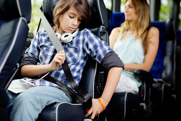 Boy adjusting seat belt while sitting in bus © Cavan for Adobe