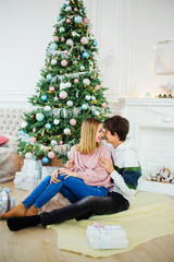 Amazing couple sitting near to a Christmas tree embracing each other