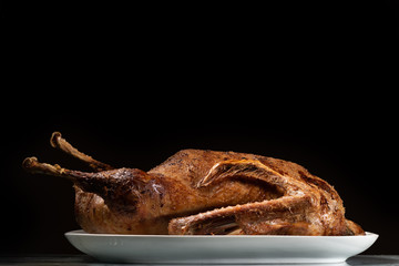 Roasted goose on a white plate black background