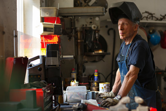 Senior man looking away while standing by workbench in workshop