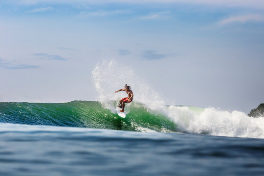 Man surfing on wave in sea against sky