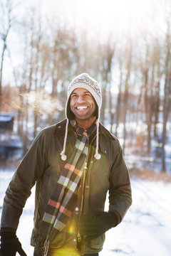 Happy man looking away while standing on snow covered field