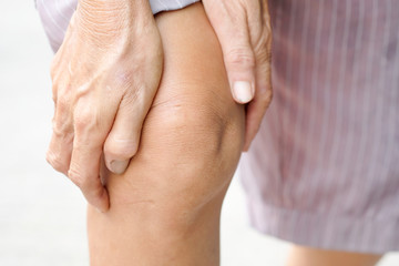 Knee pain .Woman stand on grass Her hand caught at the knee. Having painful feet and stretching muscles fatigue To relieve pain. health concepts.