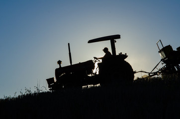 Trator plantando no p&ocirc;r do sol 